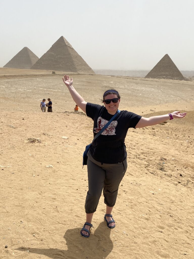 Me with my hands raised standing in front of the 3 pyramids