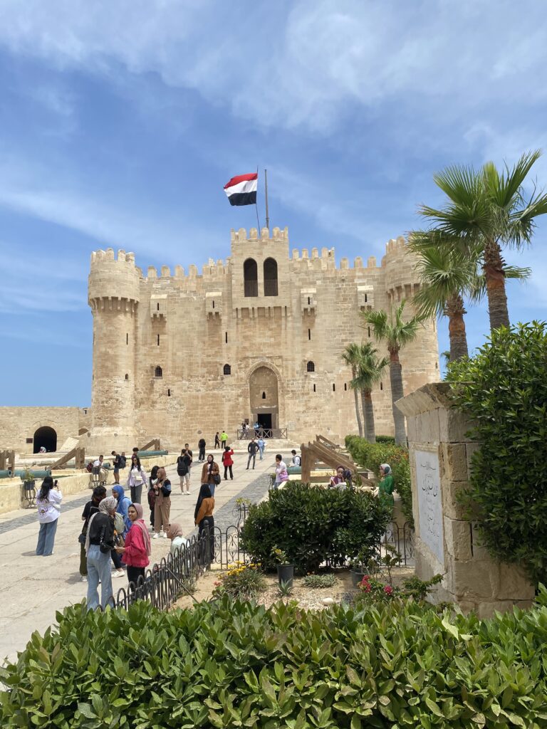 small castle looking building of light tan stone with an Egyptian flag flying at the top