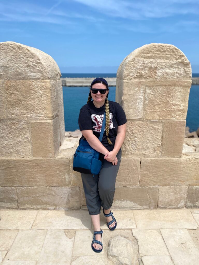 photo of me leaning on a stone ledge with the ocean in the background